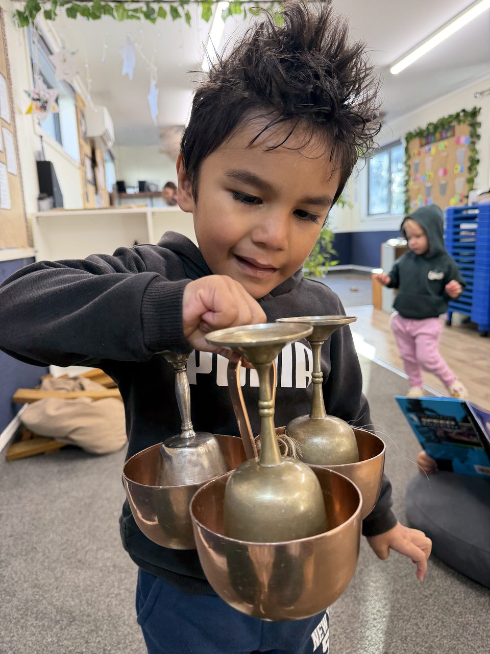 A child exploring metal vessels in an indoor learning space